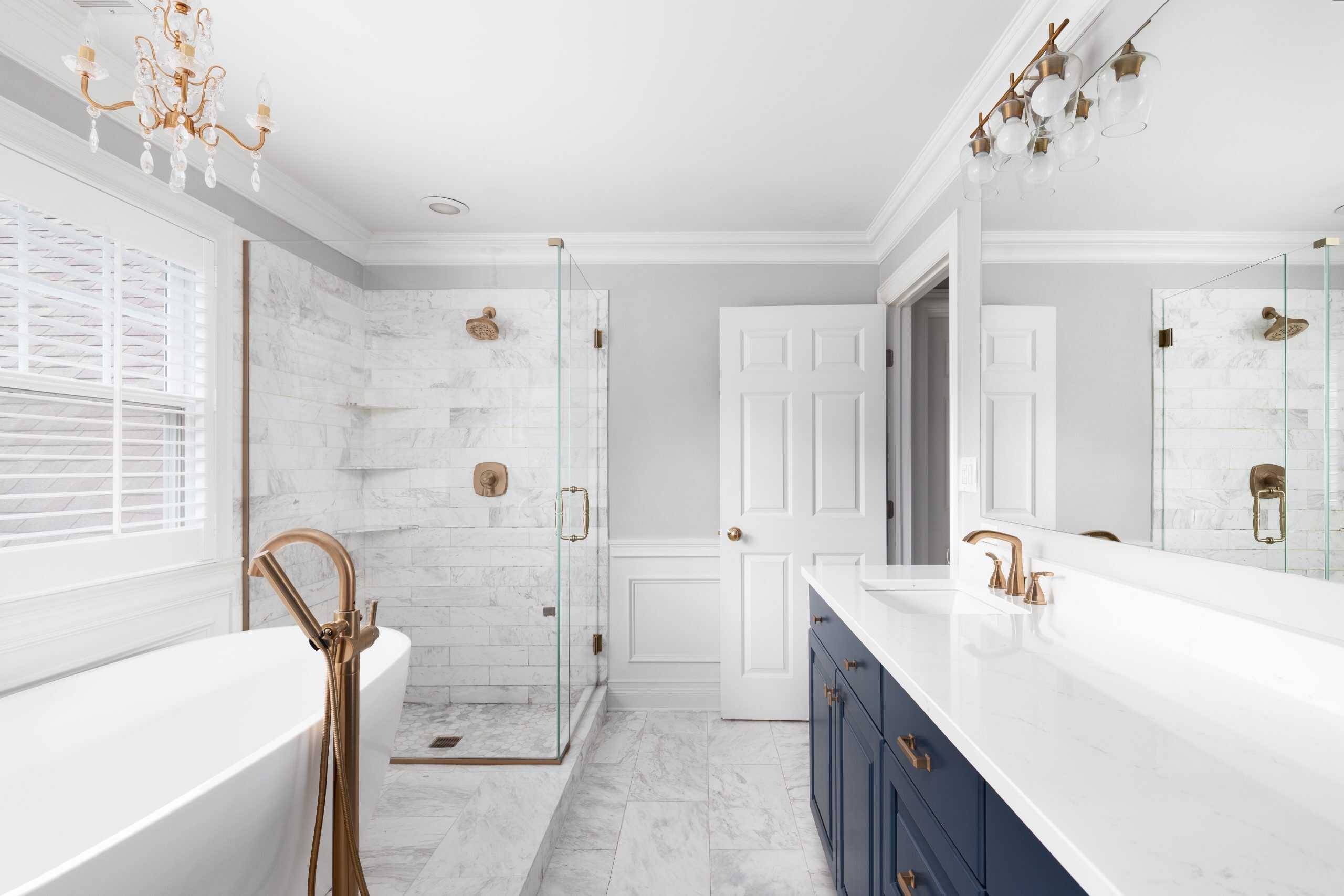 Modern white bathroom featuring blue cabinets and a gold sink faucet.