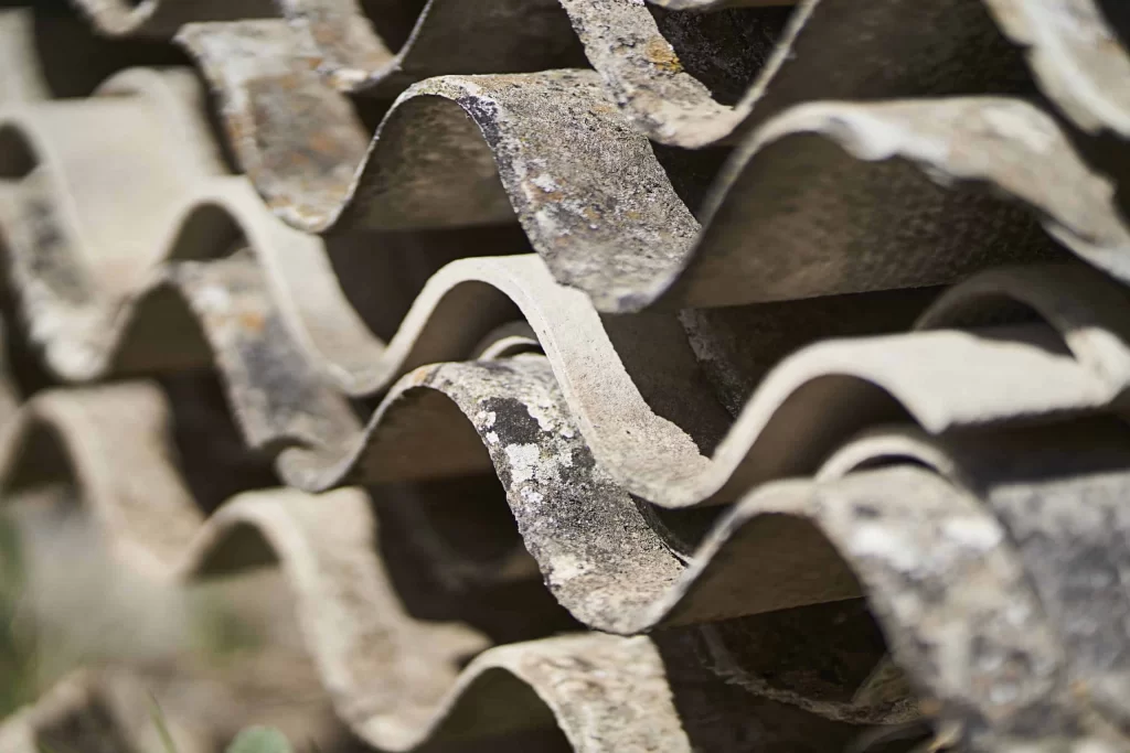 Piles of hazardous asbestos sheets marked as toxic waste awaiting safe disposal.
